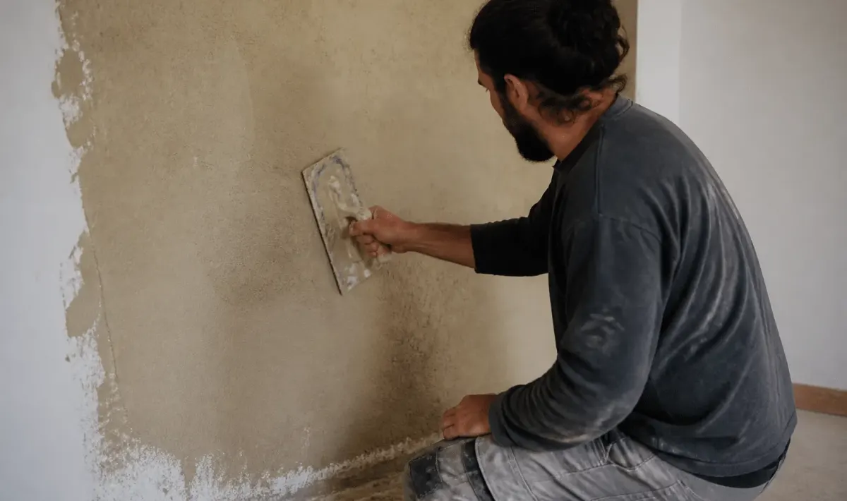 Applicateur étale enduit chanvre beige sur mur intérieur