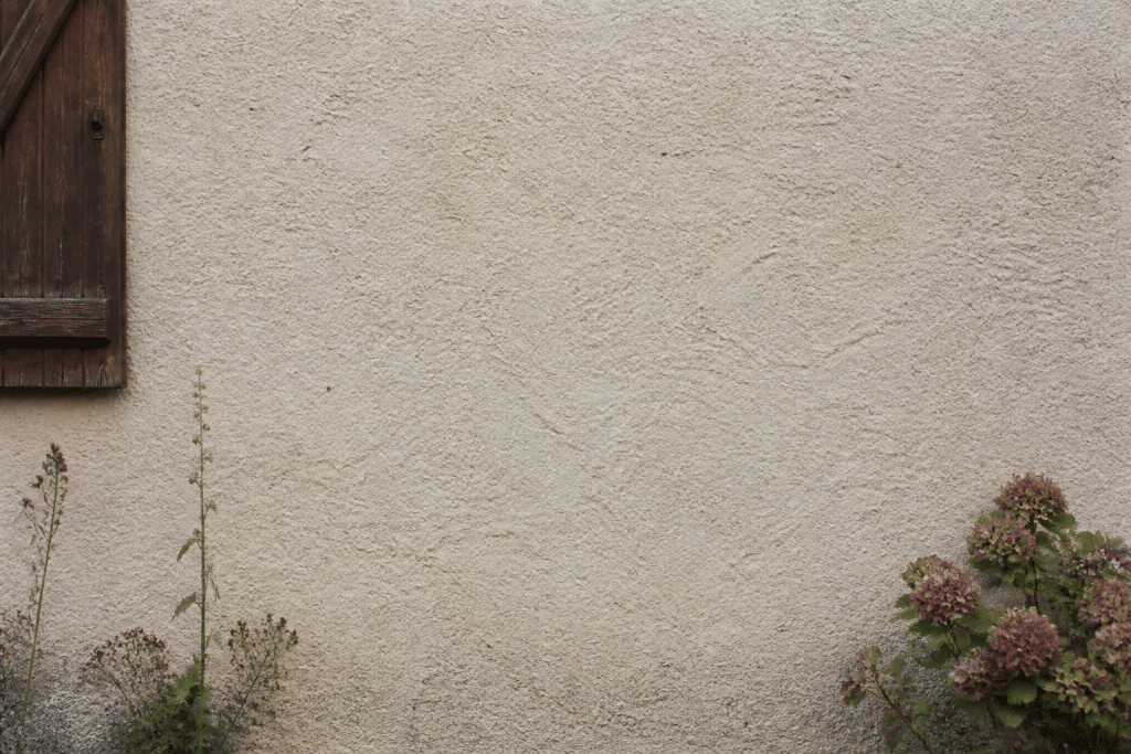 Mur pierre ancienne recouvert enduit beige clair granuleux