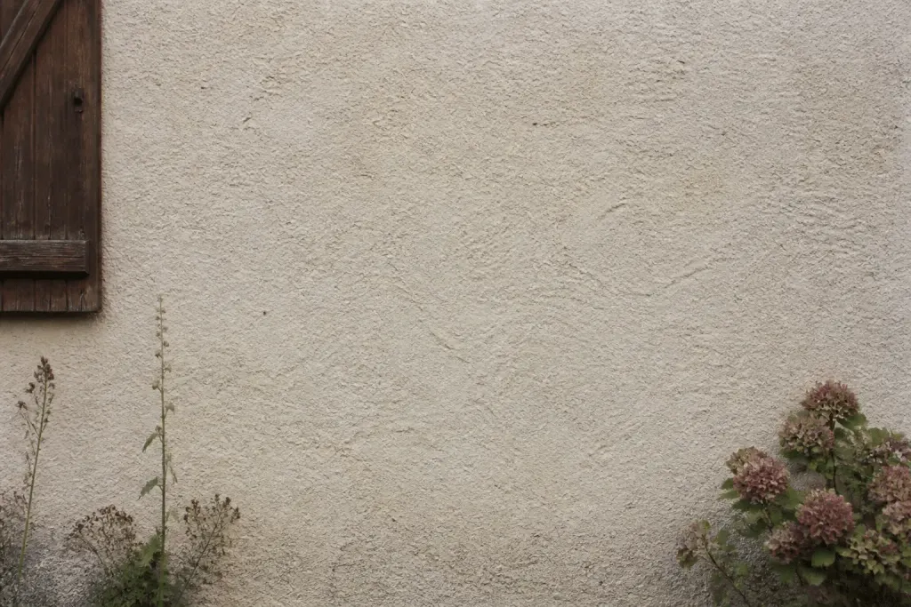 Mur pierre ancienne recouvert enduit beige clair granuleux