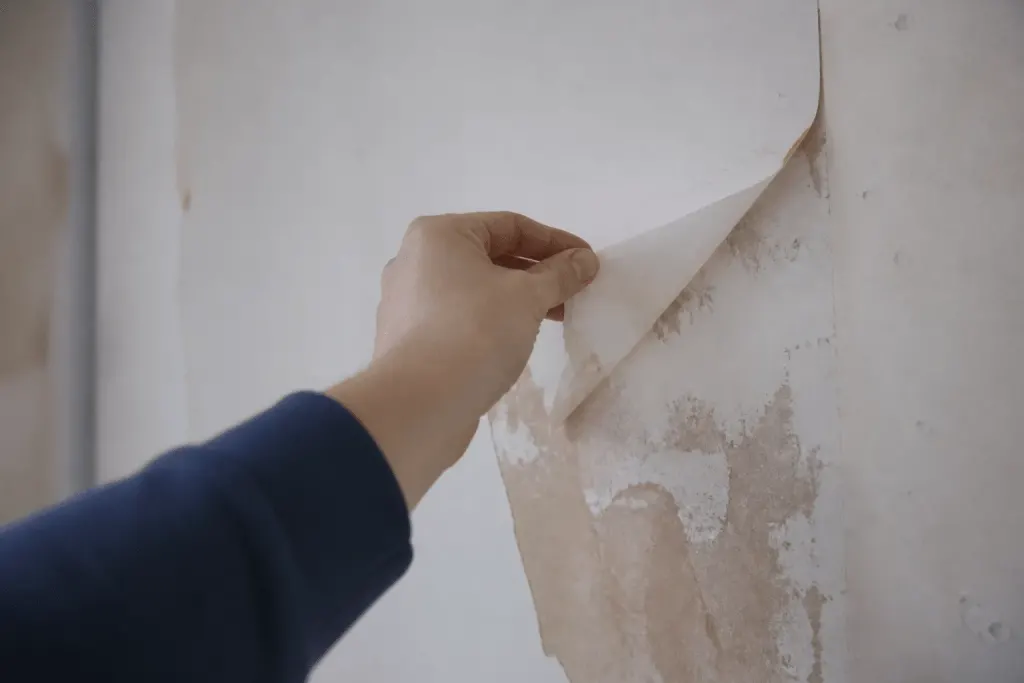 Main enlevant papier peint blanc du mur