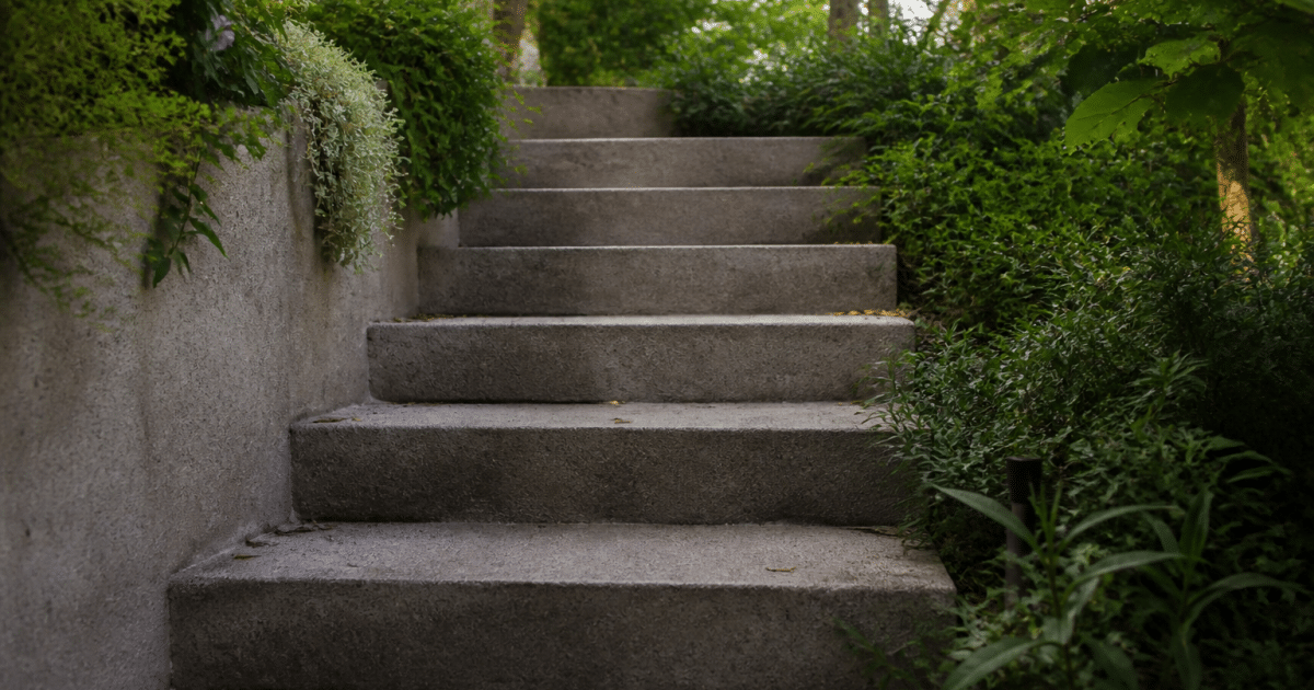Marches beton grises montant vers haut jardin exterieur