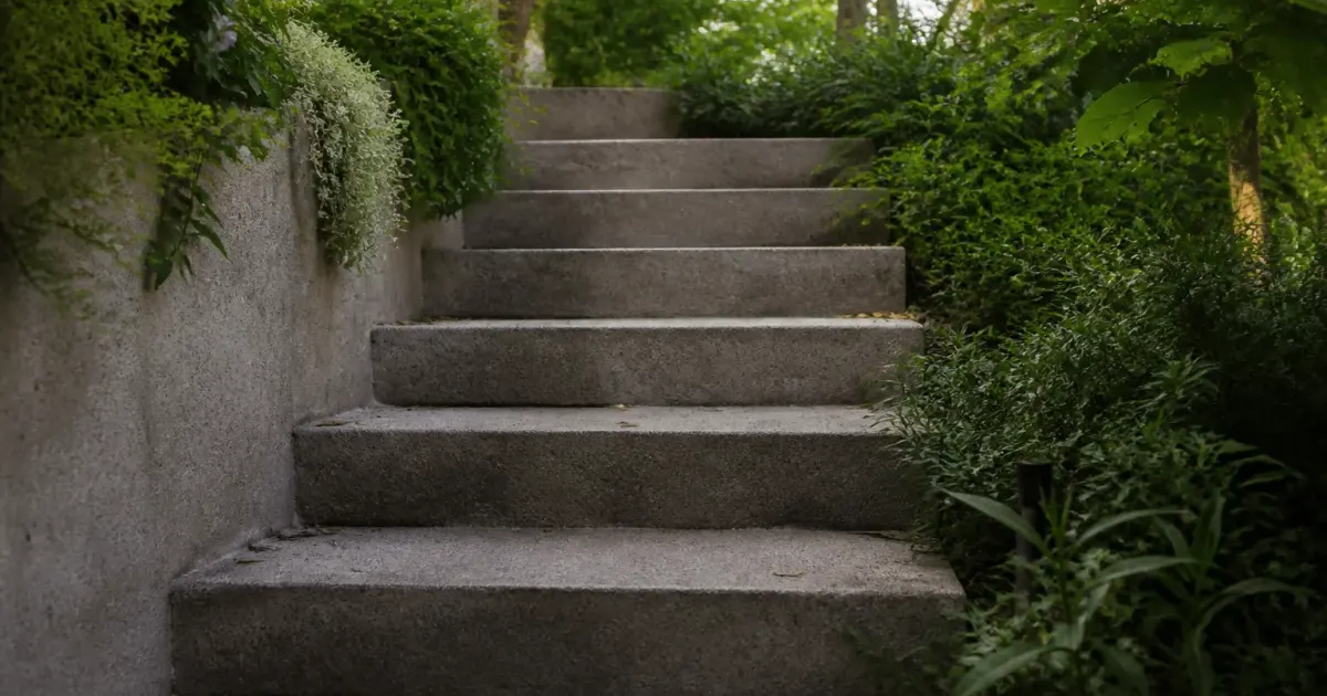 Marches beton grises montant vers haut jardin exterieur