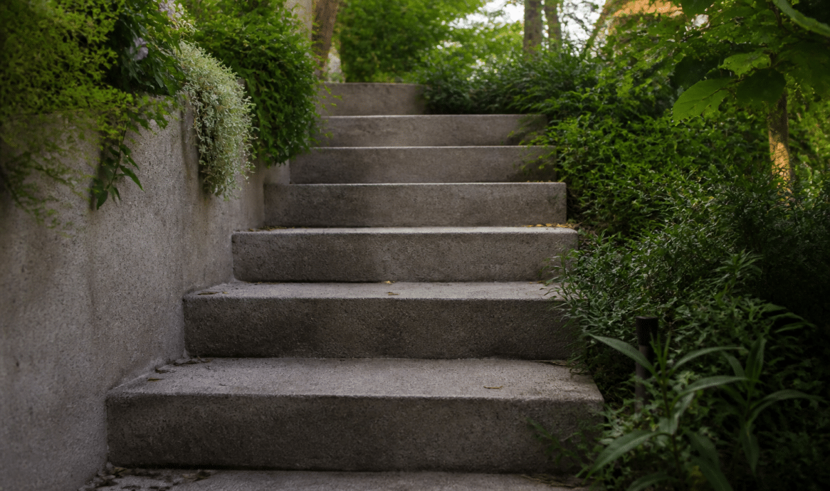 Marches beton grises montant vers haut jardin exterieur