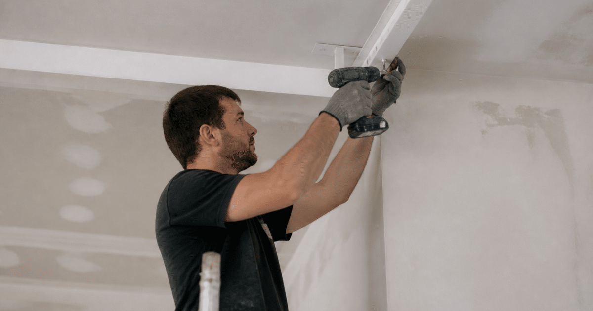 Ouvrier fixant structure metallique blanche au plafond