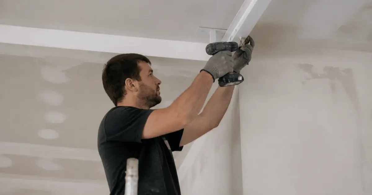 Ouvrier fixant structure metallique blanche au plafond