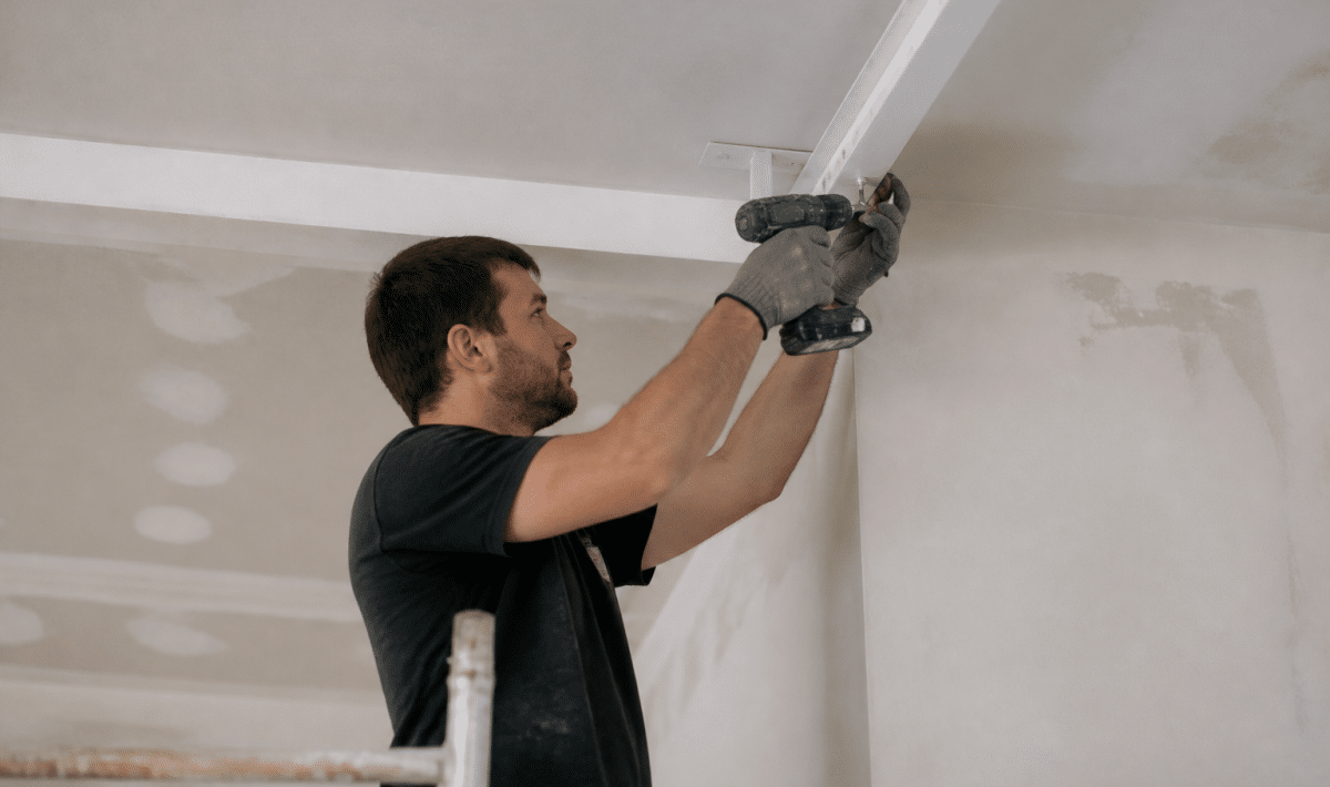 Ouvrier fixant structure metallique blanche au plafond