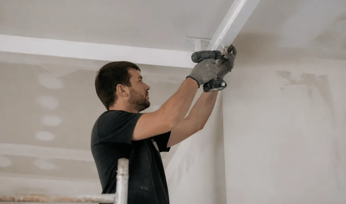 Ouvrier fixant structure metallique blanche au plafond