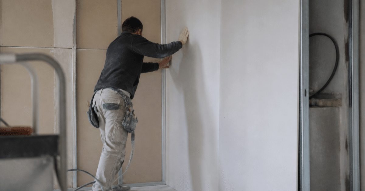 ouvrier installe plaques placo verticales sur structure murale intérieure