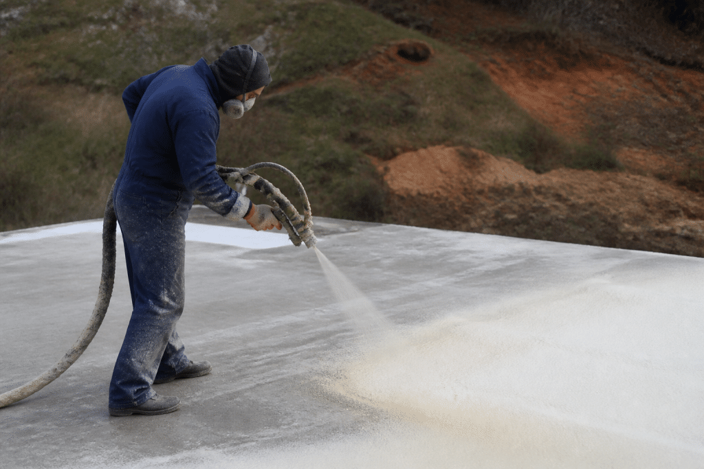 Ouvrier appliquant isolant mousse sur dalle béton grise