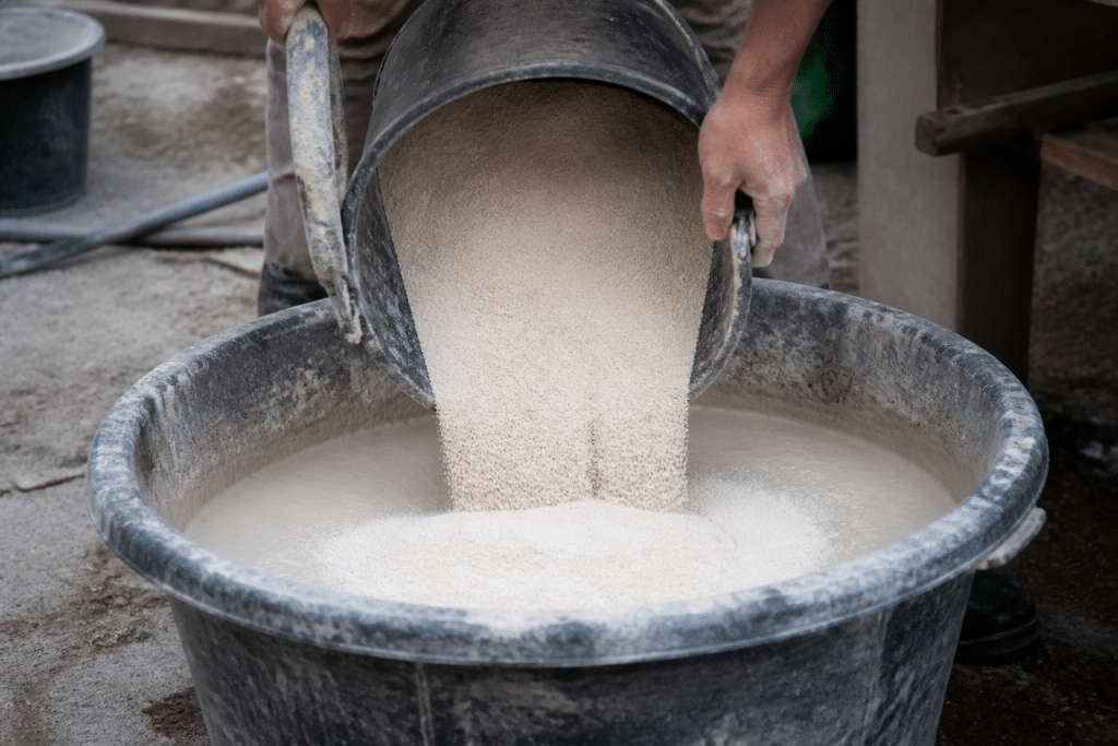 Mains versant sable blanc dans mortier chaux liquide