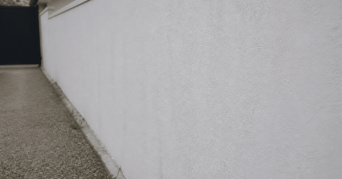 Mur exterieur en parpaing recouvert d'enduit blanc