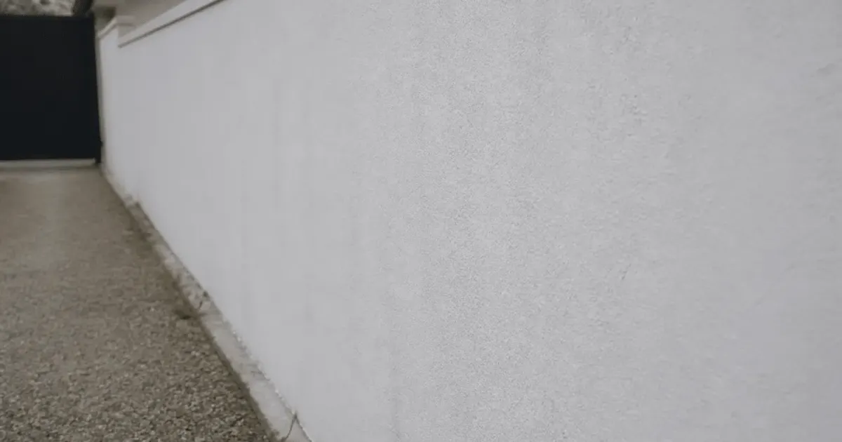 Mur exterieur en parpaing recouvert d'enduit blanc