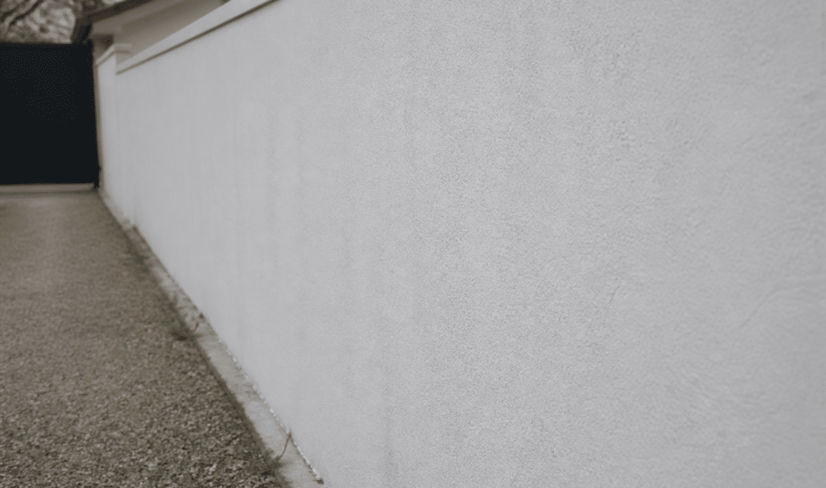 Mur exterieur en parpaing recouvert d'enduit blanc
