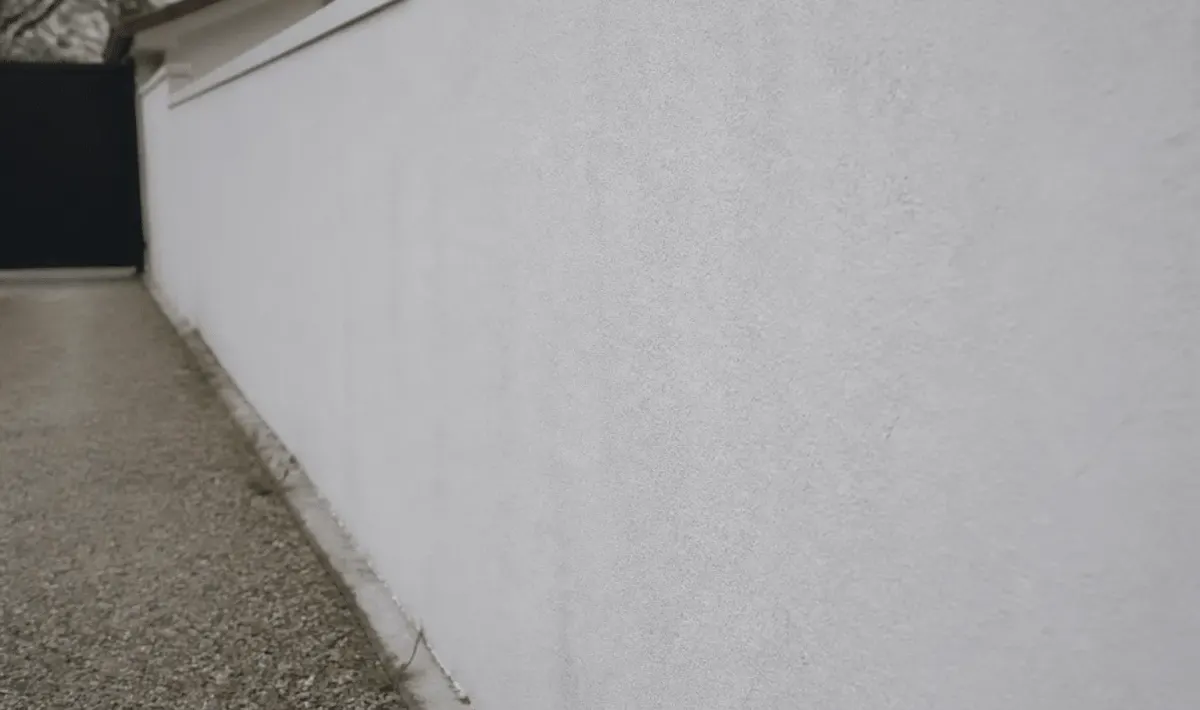 Mur exterieur en parpaing recouvert d'enduit blanc