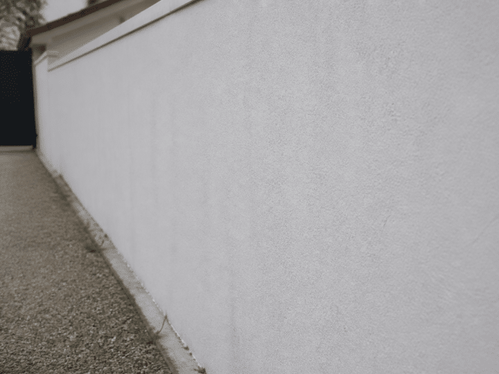 Mur exterieur en parpaing recouvert d'enduit blanc