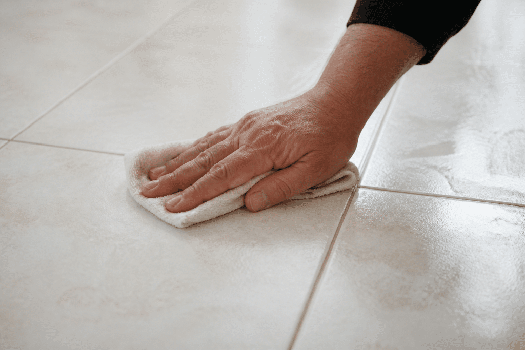 Main de personne nettoyant carrelage blanc avec chiffon humide