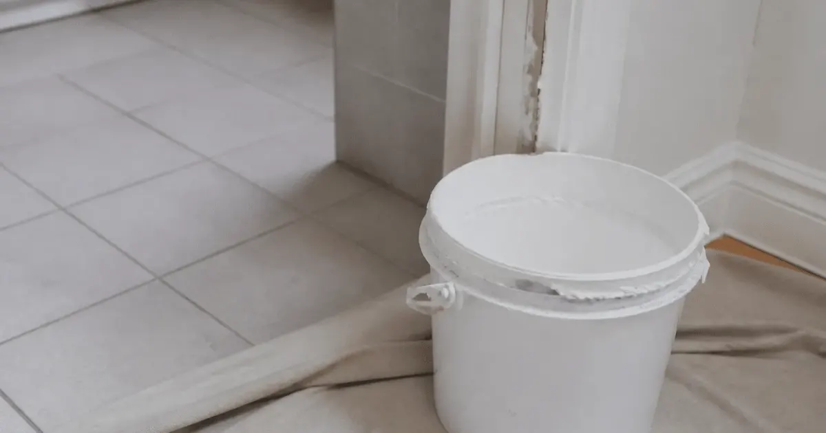 Pot de peinture blanche ouvert pres de carrelage salle bain
