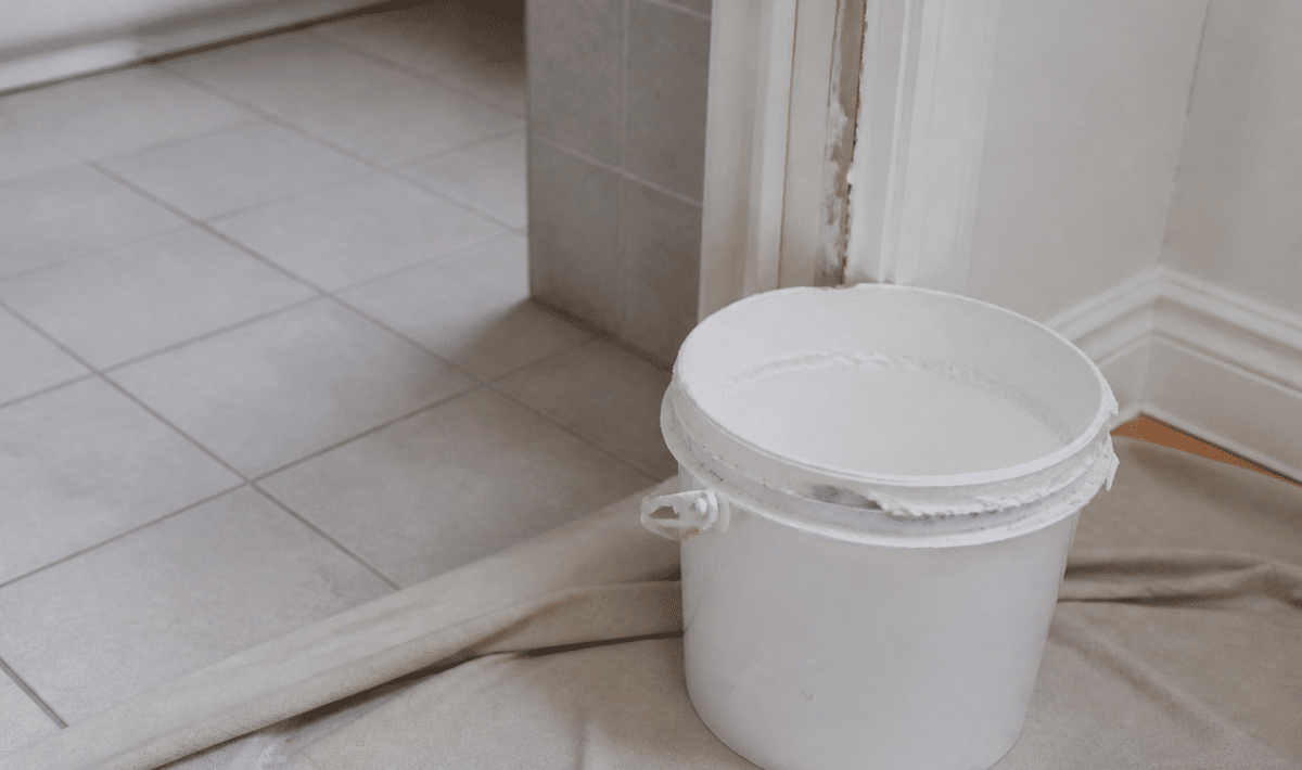 Pot de peinture blanche ouvert pres de carrelage salle bain