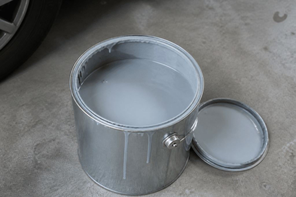 Bidon peinture epoxy ouvert sur beton gris garage