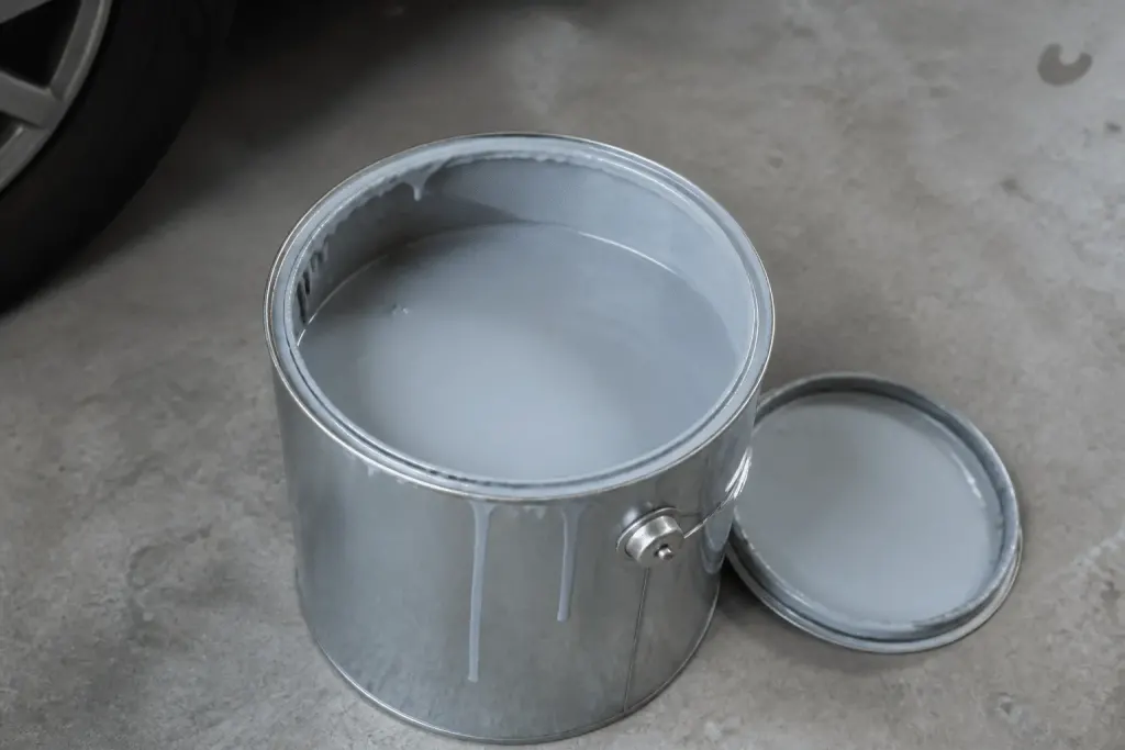 Bidon peinture epoxy ouvert sur beton gris garage