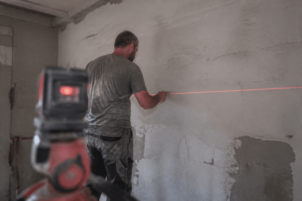 Ouvrier trace niveau horizontal mur niveau laser rouge