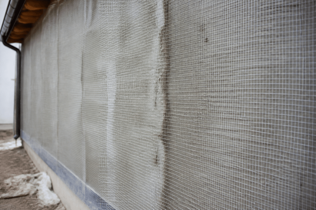 Facade with protective mesh covering drying mortar surface