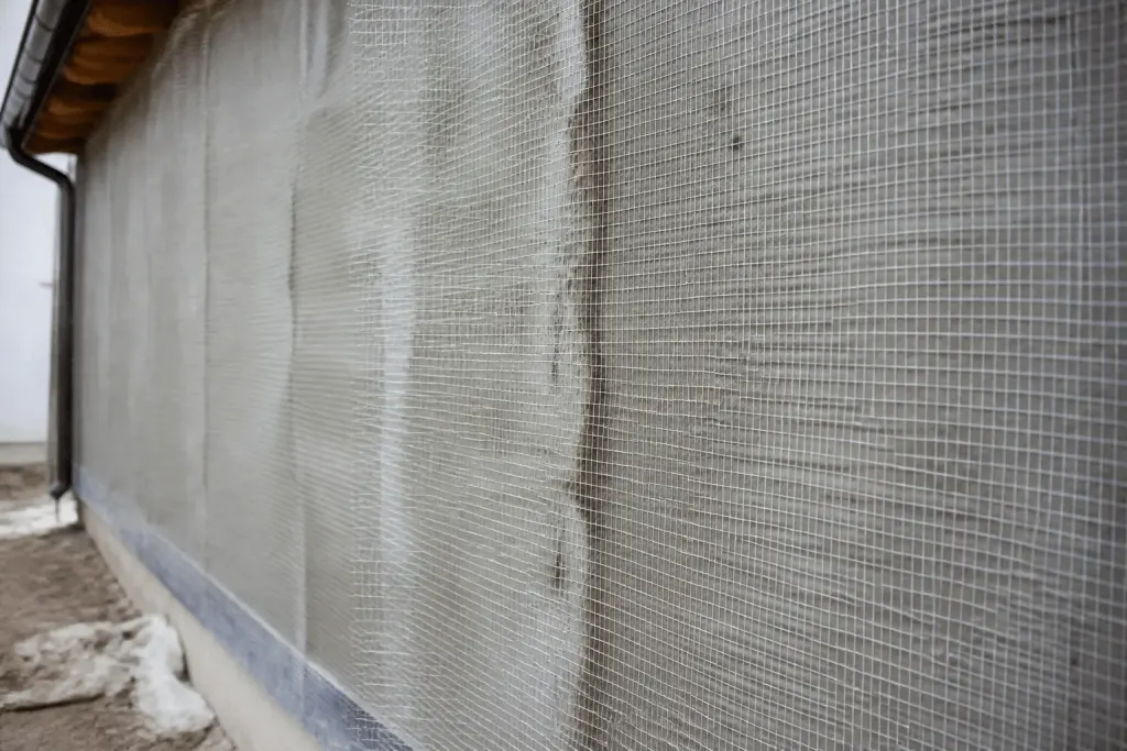Facade with protective mesh covering drying mortar surface