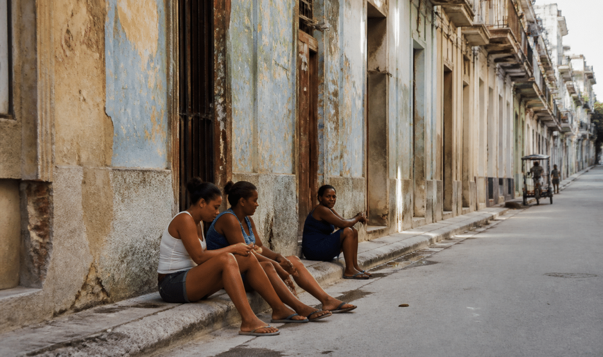 Rue urbaine avec immeubles delabres et habitants assis sur trottoir