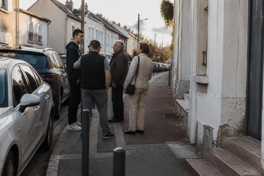 Rue de Franconville avec commerces et residents discutant en fin d'apres-midi