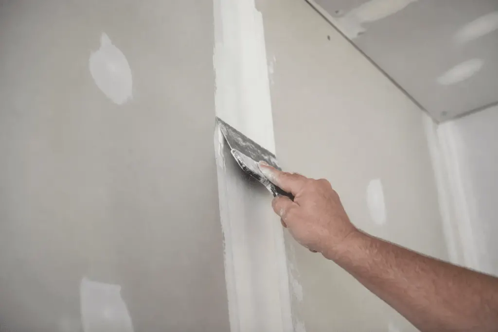 Couteau a enduire appliquant joint blanc entre plaques gypse