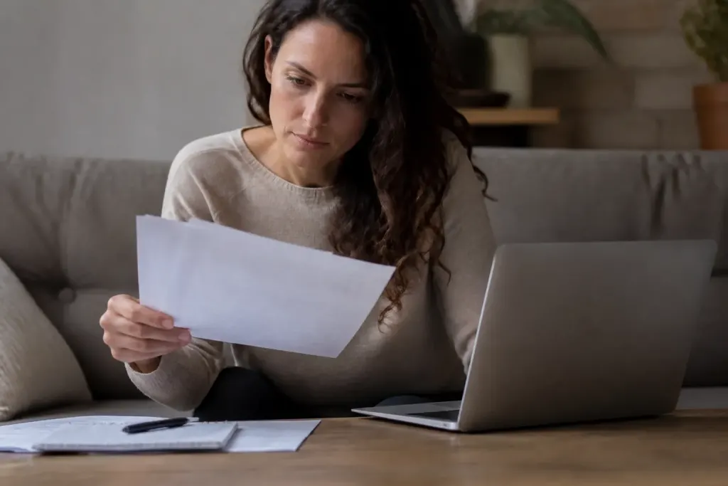 Personne examinant documents professionnels avec ordinateur portable