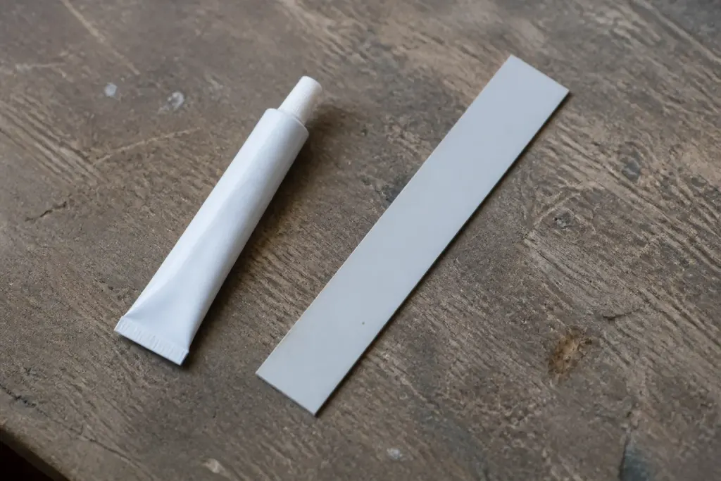 Tube de colle blanche et lame de PVC